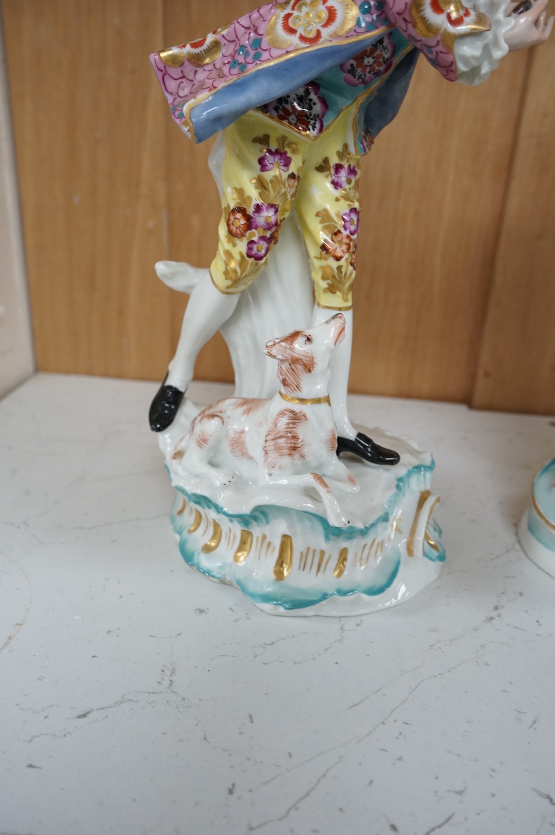 A pair of Derby style figures of a lady holding a bird cage and a gentleman holding a bird, tallest 23cm high